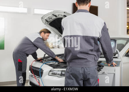 Les techniciens d'entretien d'hommes l'examen de voiture en atelier Banque D'Images