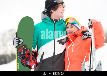 Jeune couple avec des skis et snowboard dans la neige Banque D'Images