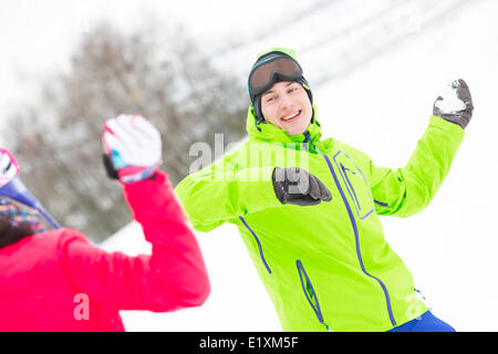 Happy young man throwing snowball vers femme Banque D'Images