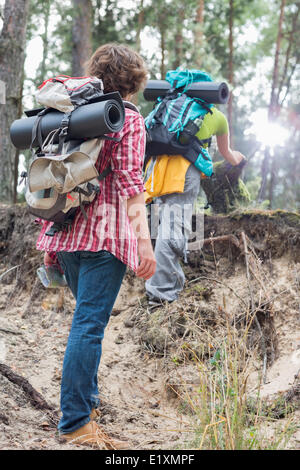 Vue arrière de l'homme regardant female hiker escalade falaise en forêt Banque D'Images