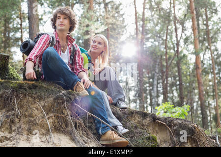 Les jeunes randonnées couple sitting on bord de la falaise en forêt Banque D'Images