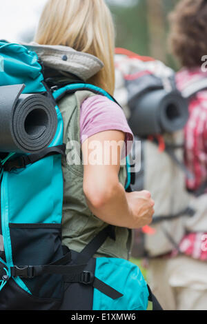 Vue arrière du female hiker exerçant son sac à dos avec l'homme en arrière-plan à l'extérieur Banque D'Images