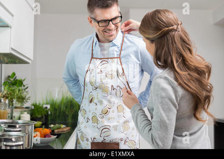 Femme Homme aidant à mettre sur un tablier de cuisine en Banque D'Images