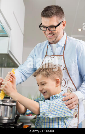 Heureux père et fils spaghetti préparation together in kitchen Banque D'Images