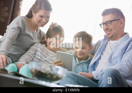 Happy Family using digital tablet together in living room Banque D'Images