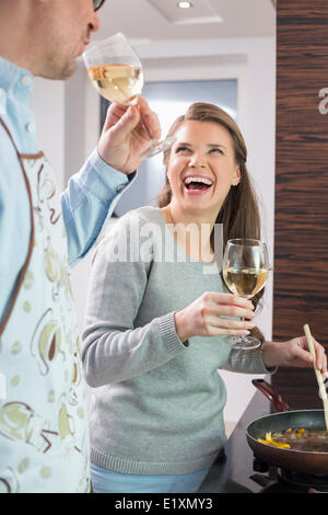 Cheerful couple having wine pendant la cuisson dans la cuisine Banque D'Images