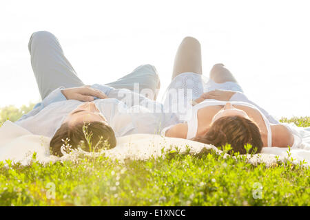 Jeune couple lying on picnic blanket in park Banque D'Images