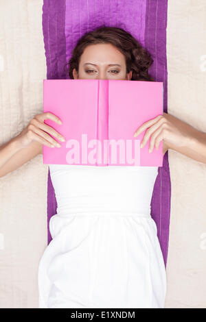 Directement au-dessus de shot of woman covering face au livre tout en lying on picnic blanket Banque D'Images