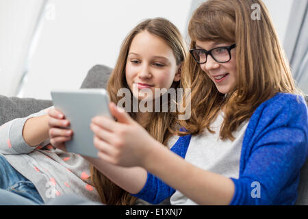 Sisters using digital tablet together at home Banque D'Images