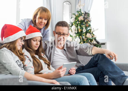 Famille de quatre using digital tablet at home during Christmas Banque D'Images