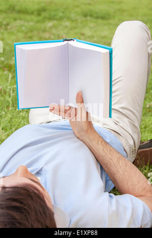 Young man holding book in park Banque D'Images