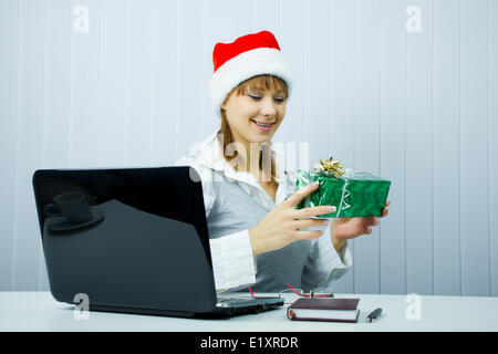 Fille de travail à Santa hat with a gift Banque D'Images