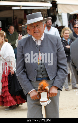 Rocio Romeria - homme sur hobby horse, reproduit une corrida avec d'autres hommes alors que les femmes en costume traditionnel andalou regarder sur Banque D'Images