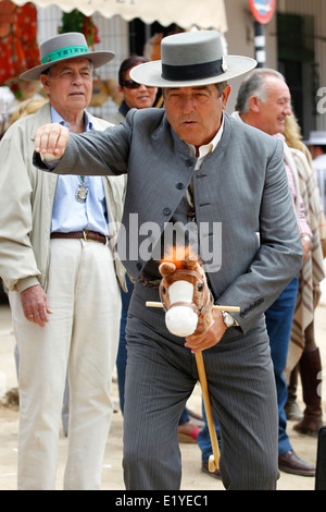 Rocio Romeria - homme sur hobby horse, reproduit une corrida avec d'autres hommes alors que les femmes en costume traditionnel andalou regarder sur Banque D'Images