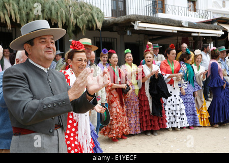 Rocio Romeria - homme sur hobby horse, reproduit une corrida avec d'autres hommes alors que les femmes en costume traditionnel andalou regarder sur Banque D'Images