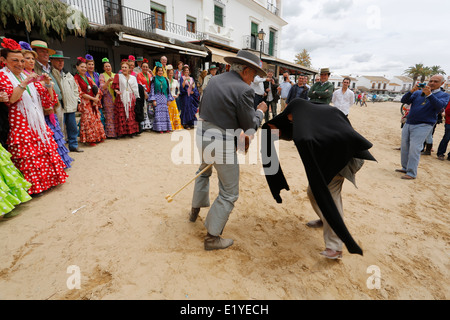 Rocio Romeria - homme sur hobby horse, reproduit une corrida avec d'autres hommes alors que les femmes en costume traditionnel andalou regarder sur Banque D'Images