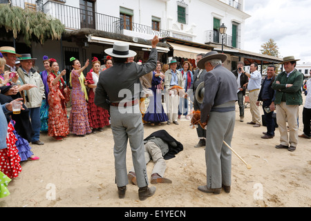 Rocio Romeria - homme sur hobby horse, reproduit une corrida avec d'autres hommes alors que les femmes en costume traditionnel andalou regarder sur Banque D'Images