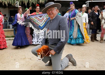 Rocio Romeria - homme sur hobby horse, reproduit une corrida avec d'autres hommes alors que les femmes en costume traditionnel andalou regarder sur Banque D'Images