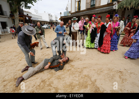 Rocio Romeria - homme sur hobby horse, reproduit une corrida avec d'autres hommes alors que les femmes en costume traditionnel andalou regarder sur Banque D'Images