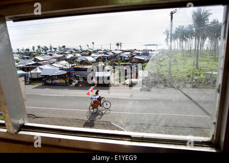 11 juin 2014 - Tacloban, Philippines - Tacloban, Philippines - un pedicab est vu en passant par le biais d'une fenêtre de verre cassée à Tacloban City le 11 juin 2014. Le 8 novembre 2013, Haiyan, l'un des plus puissant typhon à jamais frappé la terre, ravagé les Visayas orientales des milliers de morts et de sans-abri. Le gouvernement estime à 16 millions de personnes ont été touchées par le typhon, avec 6 300 morts et des milliers d'autres portés disparus. Logement et subsistance sont parmi les graves défis dans le processus de réadaptation dans les régions touchées par Haiyan sept mois après la catastrophe. (Crédit Image : © Mark Crist Banque D'Images