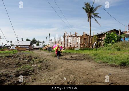 11 juin 2014 - Tacloban, Philippines - Tacloban, Philippines - Une fille marche avec un parapluie en allant à l'école à Tacloban City le 11 juin 2014. Le 8 novembre 2013, Haiyan, l'un des plus puissant typhon à jamais frappé la terre, ravagé les Visayas orientales des milliers de morts et de sans-abri. Le gouvernement estime à 16 millions de personnes ont été touchées par le typhon, avec 6 300 morts et des milliers d'autres portés disparus. Logement et subsistance sont parmi les graves défis dans le processus de réadaptation dans les régions touchées par Haiyan sept mois après la catastrophe. (Crédit Image : © Mark Cristino/NurP Banque D'Images