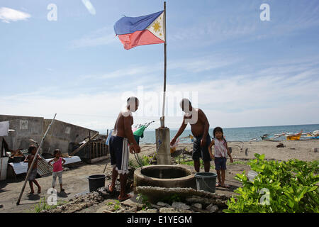 11 juin 2014 - Tacloban, Philippines - Tacloban, Philippines - Les hommes se relaient pour aller chercher de l'eau dans Tacloban City le 11 juin 2014. Le 12 juin marque le 116e jour de l'indépendance des Philippines. Le 8 novembre 2013, Haiyan, l'un des plus puissant typhon à jamais frappé la terre, ravagé les Visayas orientales des milliers de morts et de sans-abri. Le gouvernement estime à 16 millions de personnes ont été touchées par le typhon, avec 6 300 morts et des milliers d'autres portés disparus. Logement et subsistance sont parmi les graves défis dans le processus de réadaptation dans les régions touchées par Haiyan sept mois après la catastrophe Banque D'Images