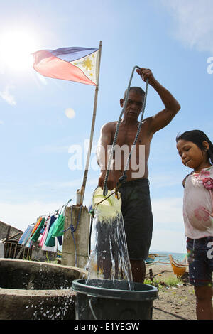 11 juin 2014 - Tacloban, Philippines - Tacloban, Philippines - Rigador Magbua, va chercher de l'eau 52 pour sa petite-fille à Tacloban City le 11 juin 2014. Le 12 juin marque le 116e jour de l'indépendance des Philippines. Le 8 novembre 2013, Haiyan, l'un des plus puissant typhon à jamais frappé la terre, ravagé les Visayas orientales des milliers de morts et de sans-abri. Le gouvernement estime à 16 millions de personnes ont été touchées par le typhon, avec 6 300 morts et des milliers d'autres portés disparus. Logement et subsistance sont parmi les graves défis dans le processus de réadaptation dans les régions touchées par Haiyan sept mon Banque D'Images