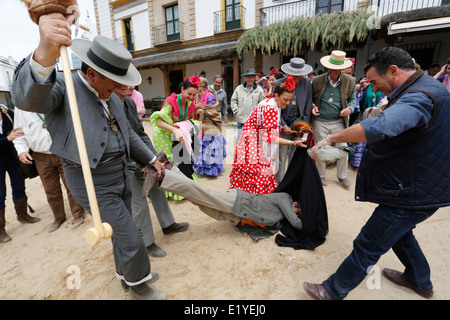 Rocio Romeria - homme sur hobby horse, reproduit une corrida avec d'autres hommes alors que les femmes en costume traditionnel andalou regarder sur Banque D'Images