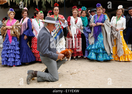 Rocio Romeria - homme sur hobby horse, reproduit une corrida avec d'autres hommes alors que les femmes en costume traditionnel andalou regarder sur Banque D'Images