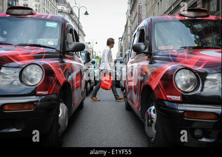 Un homme marche à travers le blocage du taxi Strand à Londres, en Angleterre, au cours d'un chauffeur de taxi protester contre le téléphone mobile app Uber. Banque D'Images