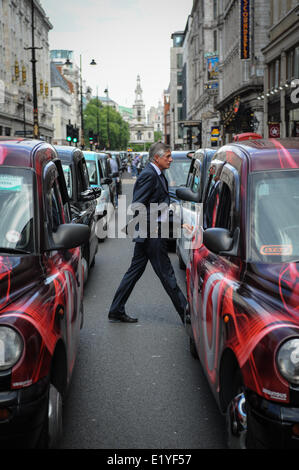 Un homme en costume de promenades à travers le blocage du taxi Strand à Londres, en Angleterre, au cours d'un chauffeur de taxi protester contre le téléphone mobile app Uber. Banque D'Images