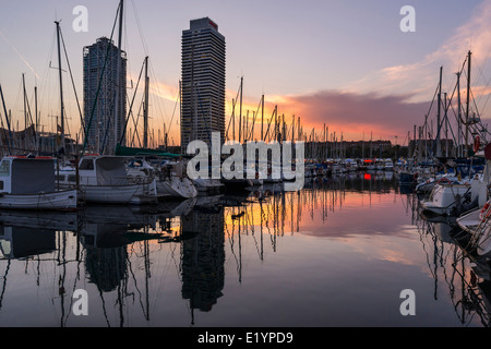 Bateaux et gratte-ciels de la Barceloneta au coucher du soleil. Banque D'Images