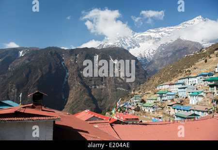 Le Népal Namche Bazarre. Les drapeaux de prières sur les bâtiments avec montagnes en arrière-plan, le Mt Everest à distance Banque D'Images