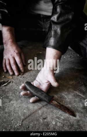 Les mains de l'homme avec un vieux couteau rouillé, Banque D'Images