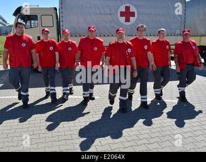 Schönefeld, Allemagne. 12 Juin, 2014. Les partisans de la Croix-Rouge allemande posent pour une photo après la préparation des véhicules pour le départ de la Croix-Rouge à l'Ukraine, convoi d'aide à la Croix Rouge centre logistique à Schönefeld, Allemagne, 12 juin 2014. Le convoi se compose de deux semi-remorques, trois cars, deux camions de 12 tonnes, un camion de 7,5 tonnes et une ambulance pour le transport des brancards, casques, sacs à dos de premiers soins, des couvertures, des tentes, des mannequins pour des cours de premiers soins ainsi que des fauteuils roulants et aides à la marche pour les personnes âgées. Dpa : Crédit photo alliance/Alamy Live News Banque D'Images