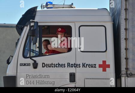 Schönefeld, Allemagne. 12 Juin, 2014. Partisans Armin Freistedt (R) et Raik Mattheis de la Croix-Rouge allemande attendre le départ du convoi d'aide de la Croix Rouge à l'Ukraine, à la Croix-Rouge centre logistique à Schönefeld, Allemagne, 12 juin 2014. Le convoi se compose de deux semi-remorques, trois cars, deux camions de 12 tonnes, un camion de 7,5 tonnes et une ambulance pour le transport des brancards, casques, sacs à dos de premiers soins, des couvertures, des tentes, des mannequins pour des cours de premiers soins ainsi que des fauteuils roulants et aides à la marche pour les personnes âgées. Dpa : Crédit photo alliance/Alamy Live News Banque D'Images