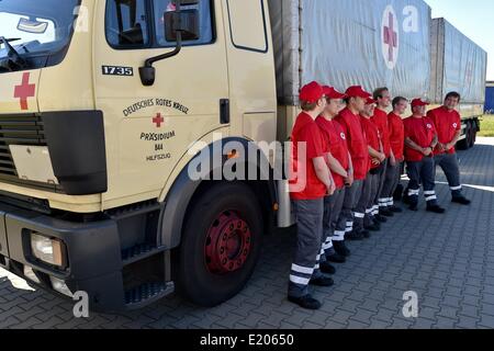 Schönefeld, Allemagne. 12 Juin, 2014. Les partisans de la Croix-Rouge allemande posent pour une photo après la préparation des véhicules pour le départ de la Croix-Rouge à l'Ukraine, convoi d'aide à la Croix Rouge centre logistique à Schönefeld, Allemagne, 12 juin 2014. Le convoi se compose de deux semi-remorques, trois cars, deux camions de 12 tonnes, un camion de 7,5 tonnes et une ambulance pour le transport des brancards, casques, sacs à dos de premiers soins, des couvertures, des tentes, des mannequins pour des cours de premiers soins ainsi que des fauteuils roulants et aides à la marche pour les personnes âgées. Dpa : Crédit photo alliance/Alamy Live News Banque D'Images