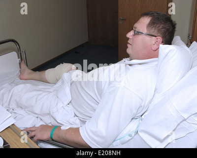 L'homme à l'hôpital avec une jambe bandée et du genou après une opération au genou Banque D'Images