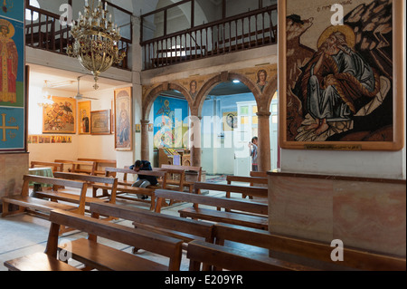 Une touriste féminine prend une photo d'un homme priant dans l'église orthodoxe grecque de Saint-Georges, Madaba. Jordanie Banque D'Images