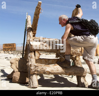 Man climbing over fence pour entrer dans une propriété privée Banque D'Images