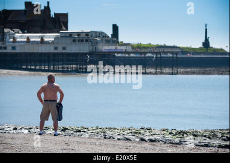 Pays de Galles Aberystwyth UK, le jeudi 12 juin 2014 avec des températures culminant à 18C (64F) sous un ciel bleu, un homme se dresse sur la plage profiter de la chaleur des sunny June météo à Aberystwyth, sur la côte ouest du pays de Galles au Royaume-Uni. Les températures devraient augmenter de 2 à 3 degrés de nouveau demain, avant que davantage de temps incertain se déplace dans le week-end photo ©keith morris Banque D'Images