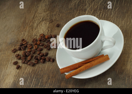 Tasse de café avec des haricots et des bâtons de cannelle sur fond de bois vieux close-up Banque D'Images