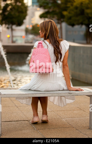 Dame féminin la modélisation d'un sac à dos en cuir rose portant chemise en denim bleu et jupe blanche Banque D'Images