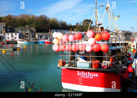 Un bateau de pêche rouge avec rouge flotte dans l'eau bleu avec le port et le bleu ciel. Banque D'Images