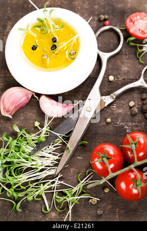 Les germes, l'ail, tomates, huile d'olive et de ciseaux sur la vieille table de cuisine Banque D'Images