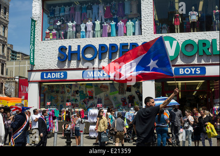 Un défilé goer vagues un drapeau Portoricain en face de Shoppers World, à la Brooklyn Puerto Rican Day Parade Banque D'Images