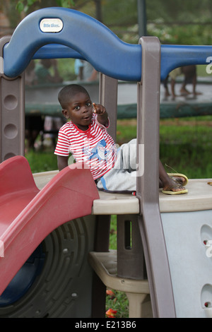 Un jeune orphelin Zambien sur une jungle gym. Banque D'Images