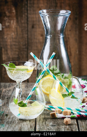 Limonade maison au citron, citron vert et menthe dans les verres avec cocktail vintage tube au-dessus de table en bois. Banque D'Images