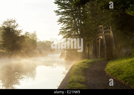 Canal et chemin de halage pont pied sur le Grand Union Canal à Braunston dans la brume matinale. Le Northamptonshire, Angleterre Banque D'Images