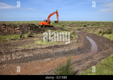 À l'aide d'un digger excavator pour la restauration de l'habitat travaux sur Deepdale Marsh, Burnham Deepdale, North Norfolk. Banque D'Images